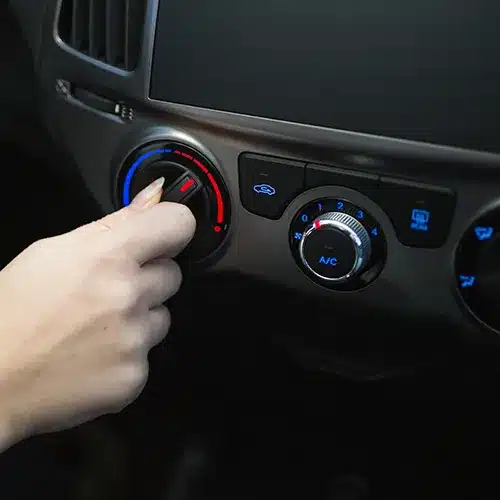 Hand Adjusting Car Climate Control Knobs Close-up of a person's hand turning a temperature control dial on a car's dashboard.