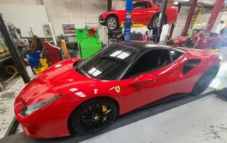 Red Ferrari on Lift in Garage Red Ferrari on a lift in a garage with tools and another car in background