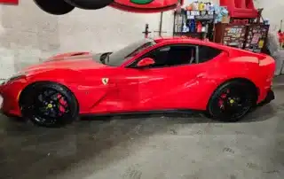 Red Ferrari Sports Car with Black Wheels Side view of a bright red Ferrari sports car with custom black wheels and red brake calipers parked indoors.