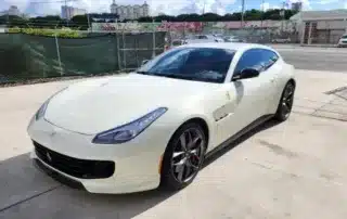 White Ferrari on City Parking Lot White Ferrari parked on concrete lot with cityscape background