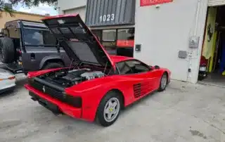 Red Ferrari with Hood Open in Front of Garage Red Ferrari with open hood parked in front of a garage