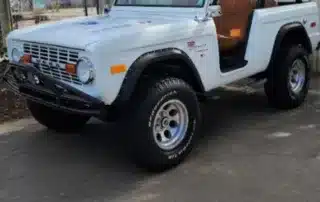 Vintage White Ford Bronco Parked on Asphalt Classic white Ford Bronco parked on asphalt with open door and brown interior
