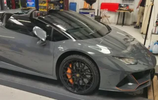 Gray Lamborghini in Garage with Orange Accents Gray Lamborghini with orange accents on wheels in a garage