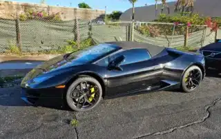 Black Lamborghini Sports Car Parked on Asphalt Sleek black Lamborghini convertible parked on cracked asphalt