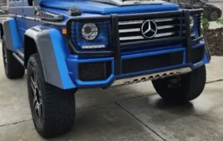 Blue Mercedes G Wagon with JFM Motorcars Logo Bright blue Mercedes G Wagon parked outdoors with JFM Motorcars logo and West Palm Beach, FL location visible.