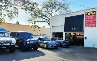 JFM Motorcars of The Palm Beaches Dealership with Luxury Cars JFM Motorcars of The Palm Beaches dealership exterior featuring a Ford Bronco, Mercedes G-Wagen, and two Porsche sports cars.