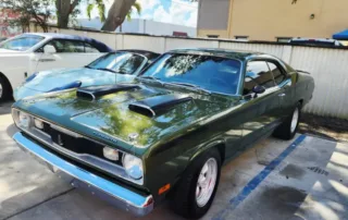 Vintage Green Dodge Dart Muscle Car Parked Outdoors A vintage green Dodge Dart muscle car with prominent hood scoops parked in an outdoor lot.
