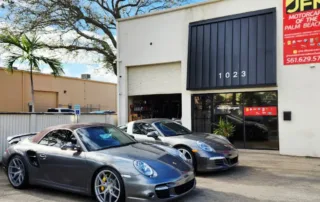 Luxury Porsche 911 Sports Cars at JFM Motorcars Showroom in Palm Beach Two grey Porsche 911 luxury sports cars, including a convertible, with yellow calipers parked outside JFM Motorcars in Palm B