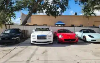 Luxury Car Collection: Ferrari, Rolls-Royce, Porsche, Mustang Four luxury cars parked in a lot: a black Ford Mustang, a white Rolls-Royce, a red Ferrari, and a light blue Porsche.